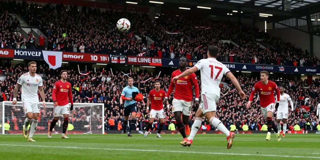 แมนยู vs ลิเวอร์พูล 10 นัดล่าสุด intense match scene with players battling for the ball and passionate fans cheering in the stadium.