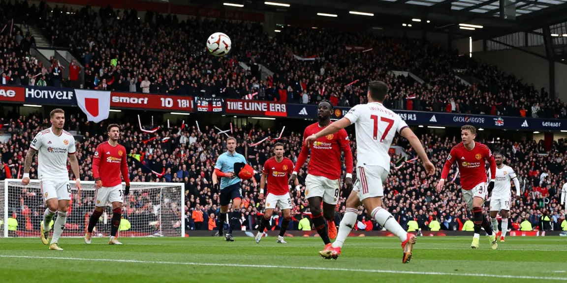 แมนยู vs ลิเวอร์พูล 10 นัดล่าสุด intense match scene with players battling for the ball and passionate fans cheering in the stadium.
